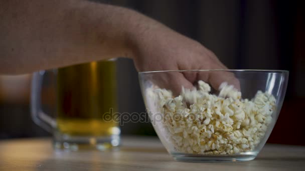 Mans hand tar popcorn från skålen, manlig dricka öl och titta på film — Stockvideo