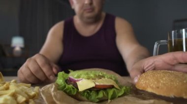 Böylece aşırı yeme, obez adam yemek büyük hamburger, yemeğini, yakın çekim hayran gurme
