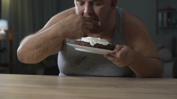 Dospělých s nadváhou muž hltání dort a lízala jeho prsty, diabetes, nezdravé jídlo — Stock video