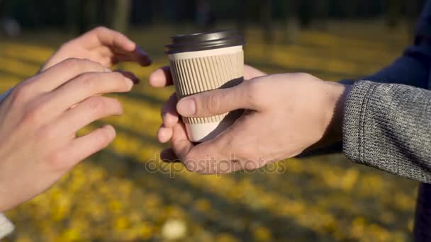 El chico cariñoso tratando a su amada con bebida caliente para ir durante la fecha en el parque — Vídeos de Stock