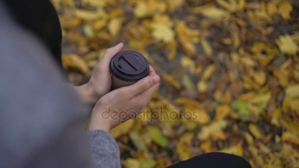 Solitário cara aquecendo mãos congeladas com bebida quente, coração partido no outono frio — Vídeo de Stock