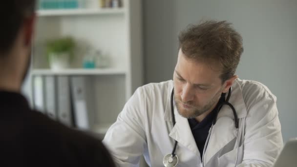 Médico masculino conversando com paciente e ouvindo batimentos cardíacos com estetoscópio — Vídeo de Stock