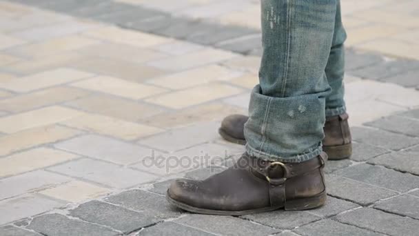 Man with brown boots and ripped jeans standing next to motorcycle, tough biker — Stock Video