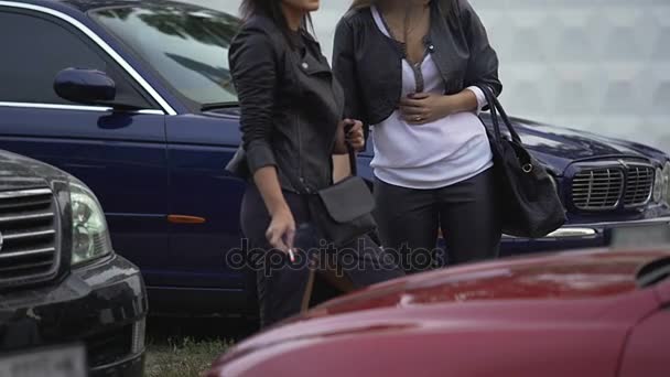 Dos mujeres delgadas fumando cigarrillos en el estacionamiento al lado del club, descanso para chicas — Vídeo de stock