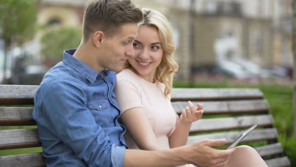 Students in love sitting on bench, using laptop, choosing where to spend summer — Stock Video