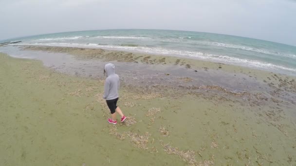 Junge Frau geht am Strand spazieren und denkt über das Leben nach, Drohnenschuss aus der Luft — Stockvideo