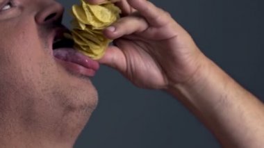 Şişman adam ağzına, patates cipsi yığını koyarak akşam yemeği Tv önünde