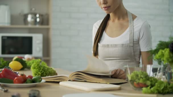 Donna asiatica che legge il libro di cucina e sceglie la ricetta dell'insalata, cibo sano — Video Stock