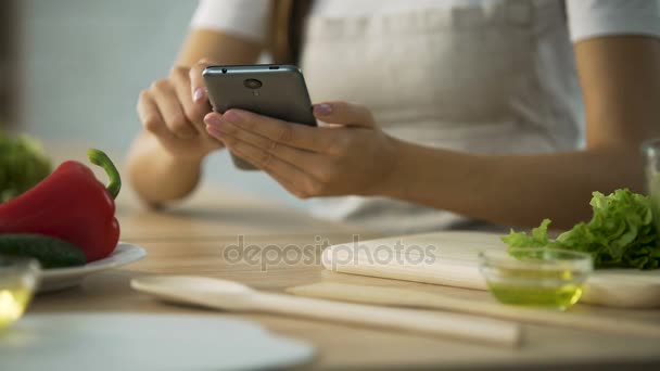 Close-up de mãos femininas rolando no smartphone, mulher escolhendo receita de salada — Vídeo de Stock