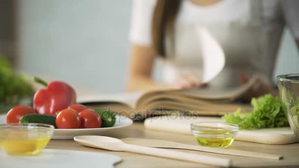 Primer plano de la chica hojeando páginas de libros de cocina, eligiendo la receta de ensalada — Vídeo de stock
