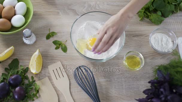 Female baker adding egg into the bowl with flour, mixing all ingredients — Stock Video