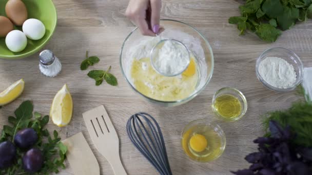 Chef sieben vor dem Kneten Mehl über die Glasschüssel mit Eiern, Draufsicht — Stockvideo