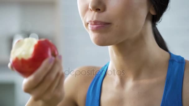 Девушка ест яблоко пополняя свое тело витаминами после изнурительной тренировки — стоковое видео