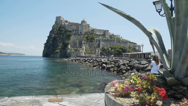 Ischia, Italië - Circa maart 2016: Toeristen in de stad. Panorama van prachtige middeleeuwse Argonese kasteel staande op vulkanische rotsachtige eilandje — Stockvideo