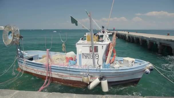 Ischia, Italien - Circa mars 2016: Transporter i staden. Trä båt med fiskeutrustning på däck flyter på vågor nära pier — Stockvideo