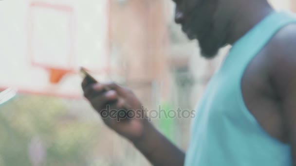 Man met smartphone, die op het basketbalveld, sportweddenschappen van toepassing — Stockvideo