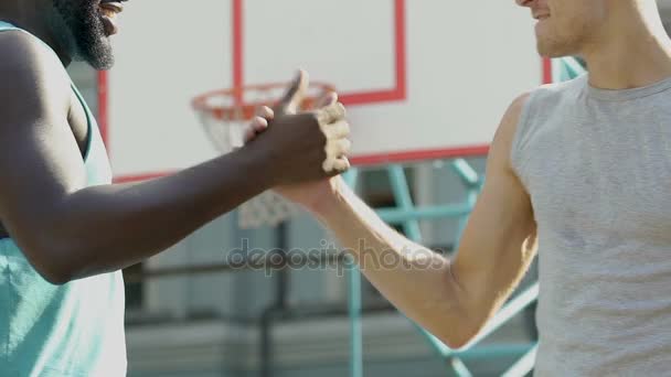 Двое друзей здороваются друг с другом, пожимая друг другу руки перед баскетболом. — стоковое видео