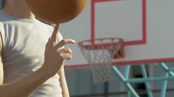 Gespierde Kaukasische atleet meesterlijk spinnen basketbal aan zijn vinger, truc — Stockvideo