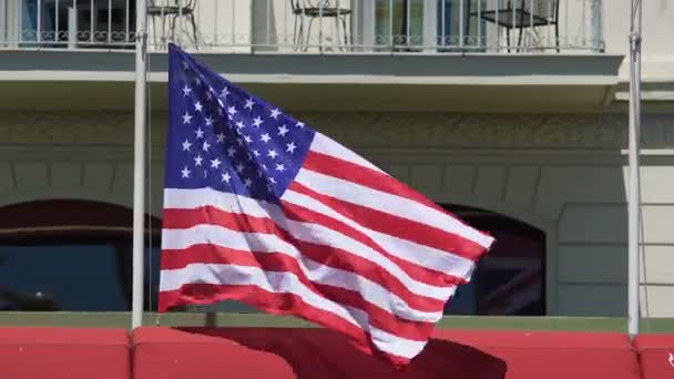 NICE, FRANCIA - CIRCA JUNIO 2016: Banderas en edificios. Primer plano de la bandera estadounidense ondeando en el poste con un fuerte viento frente al edificio — Vídeo de stock