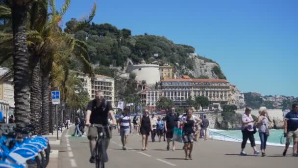 NICE, FRANCIA - CIRCA GIUGNO 2016: Persone in città. Strada trafficata lungo il lungomare nella soleggiata giornata ventosa, persone e motociclisti che si muovono — Video Stock