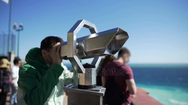 Young man looking through binoculars at observation deck and leaving, tourism — Stock Video