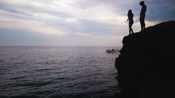 Miłości para stoi na skraju skały i przygotowanie do wskoczenia do wody — Wideo stockowe