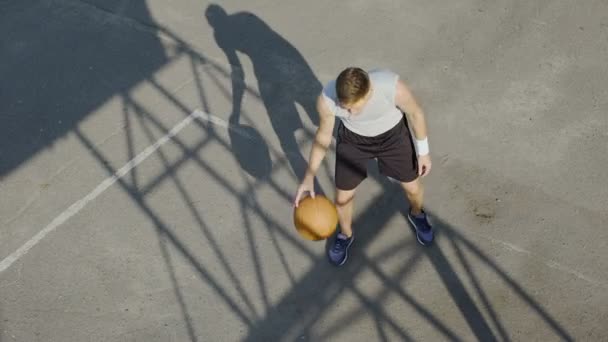 Giovane uomo che gioca a basket da solo, dribbling una palla e praticare tiri liberi — Video Stock