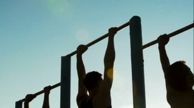 Aktif yapamadın çubuklarında açık havada, pull-up yapıyor üç güçlü sporcular spor