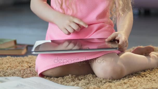 Lilla curly flicka sitter på mattan och rullning på tablett, pedagogisk app — Stockvideo