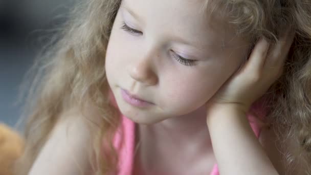 Bel viso di sorridente bionda bambina che legge un libro con interesse, primo piano — Video Stock