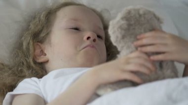 Yatakta yatarken, onun oyuncak ayı sarılma ve yetimhaneye ağlayan küçük kıvırcık çocuk