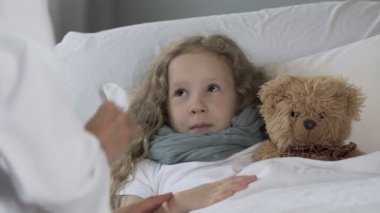 Sevimli sarışın çocuk stetoskop, closeup Doktor muayene kızla yatakta yalan