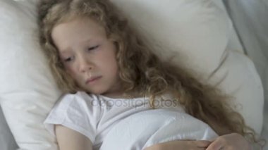Yatakta yatan ve hapları doktorun elinde, hastalık bakarak üzgün beyaz çocuk