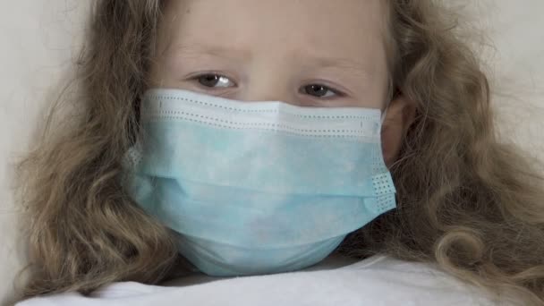 Seriously ill female kid in medical mask looking at syringe with scared eyes — Stock Video