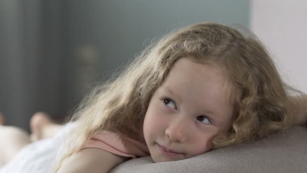 Bambino felice sdraiato sul divano e sorridente, guardando i suoi genitori con amore — Video Stock