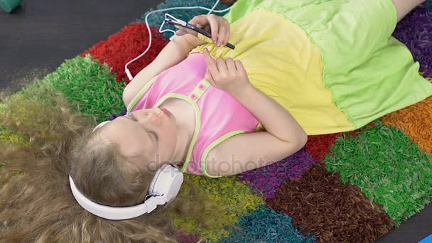 Очаровательная дочь слушает музыку в больших белых наушниках, технологии — стоковое видео