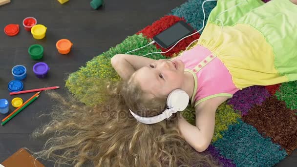 Jovem menina sorridente cantando música favorita em grandes fones de ouvido brancos, prazer — Vídeo de Stock