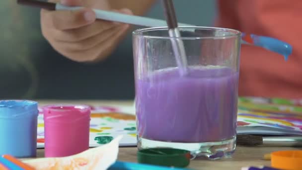 Tiny girl's hand washing painting brush in colorful water, creative fun time — Stock Video