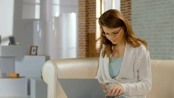 Femeie tânără în ochelari care lucrează pe laptop acasă, vedere proastă, freelance — Fotografie, imagine de stoc