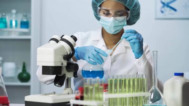 Biyokimyasal araştırma yapıyor ve mavi sıvı örnek alarak genç doktor laboratuvar