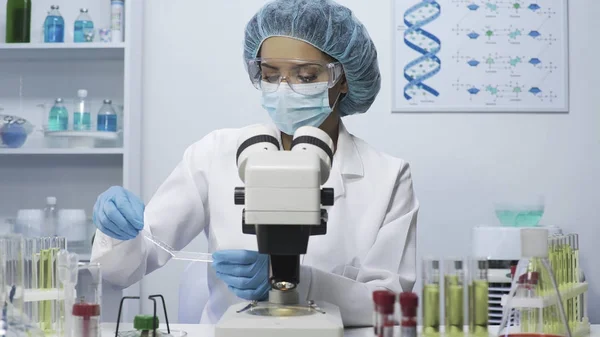 Científico de laboratorio Biracial haciendo investigación médica, mirando la pieza de vidrio — Foto de Stock