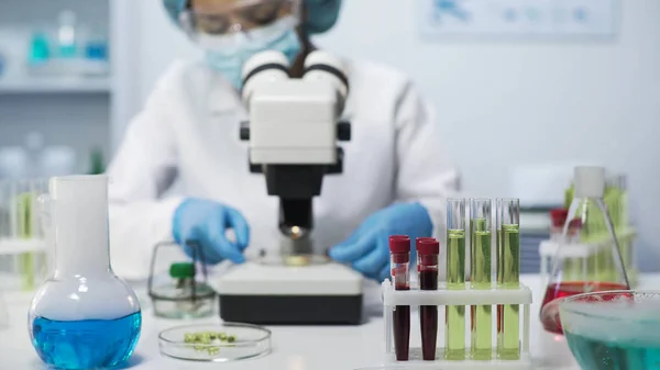 Blandad ras vetenskapsman visar prover av mikroorganismer i mikroskopet, analys — Stockfoto