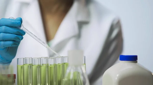 Female lab analyst checking biological material on viruses using pipette — Stock Photo, Image