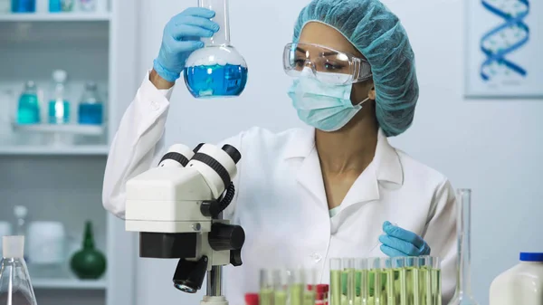Cientista birracial olhando para o microscópio, fazendo pesquisa biomédica — Fotografia de Stock