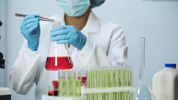 Kvinnliga lab assistent sätta reagens i kolven, kosmetologi forskar — Stockfoto