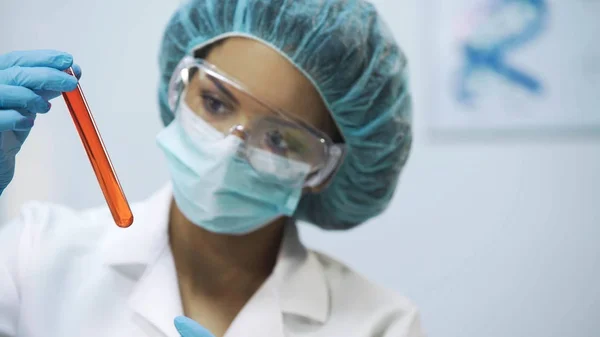 Practicante de raza mixta analizando nuevo líquido vacunal en tubo, experiencia médica — Foto de Stock