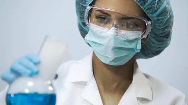 Química femenina sosteniendo frasco con líquido azul evaporador en la mano, experimento — Foto de Stock