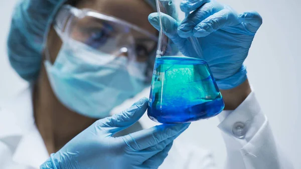 Forskare tittar på kemisk reaktion efter att lägga till testmaterialet i kolv — Stockfoto