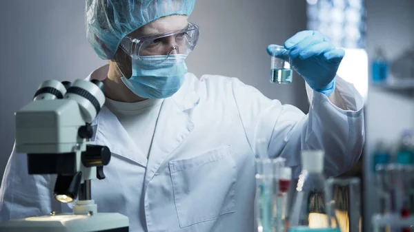 Técnico de laboratório examinando amostra de fluido para a presença de sedimentos desnecessários — Fotografia de Stock