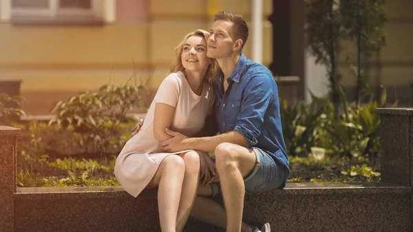 Романтическая пара сидит на скамейке и смотрит в счастливое будущее, нежные чувства — стоковое фото